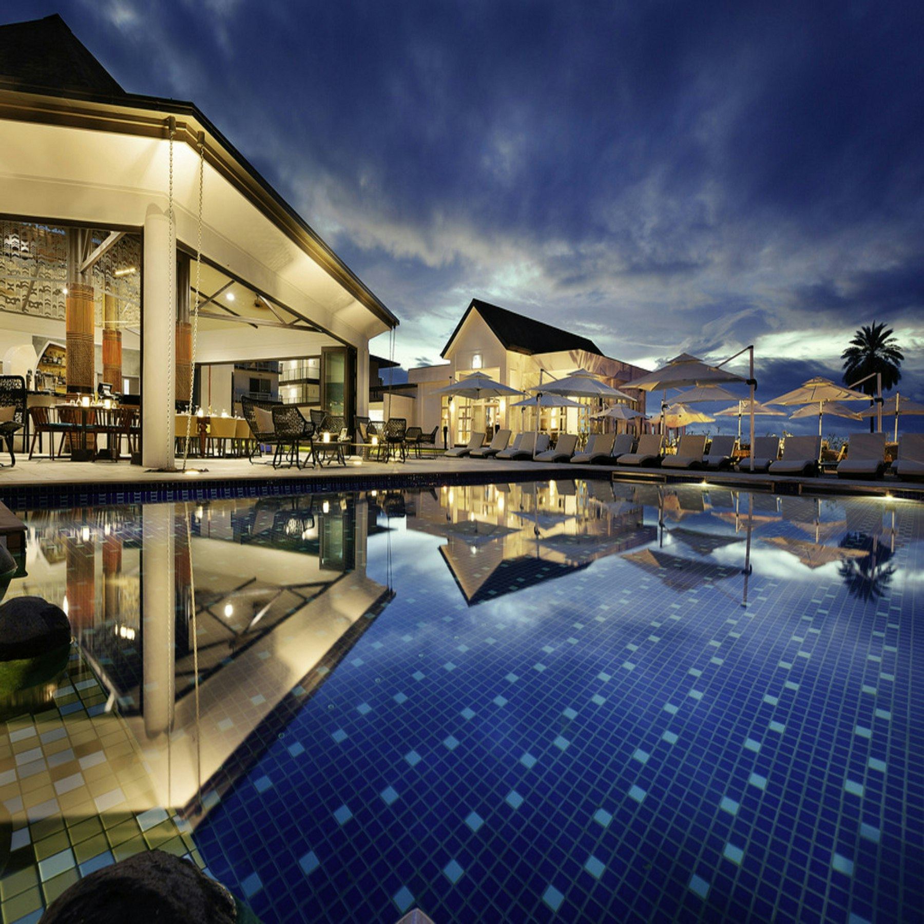 A warmly lit hotel terrace and pool at dusk, representing the stays PGP arranges in Abuja
